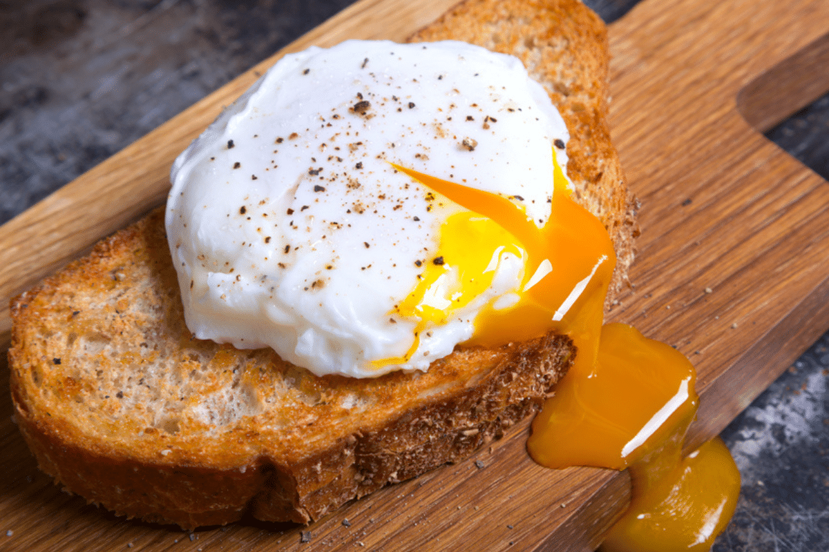 Poširano jajce, postreženo na rezini toasta na lesenem pultu