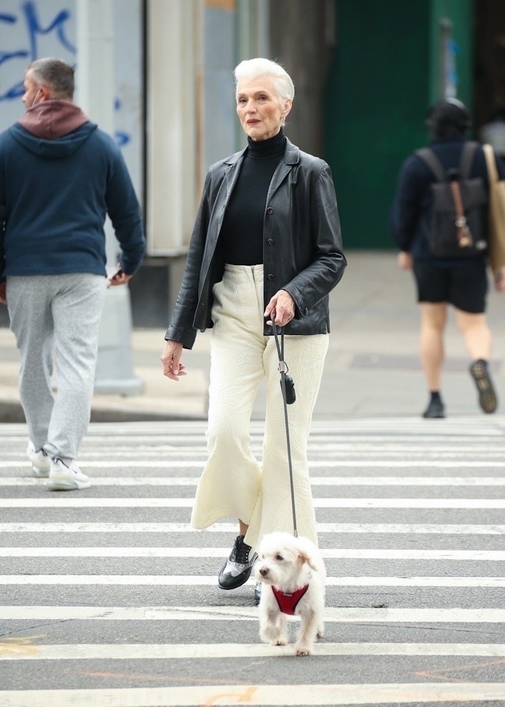 Maye Musk, oblečena v črn usnjen plašč z elegantnimi hlačami, sprehaja svojega psa v New Yorku